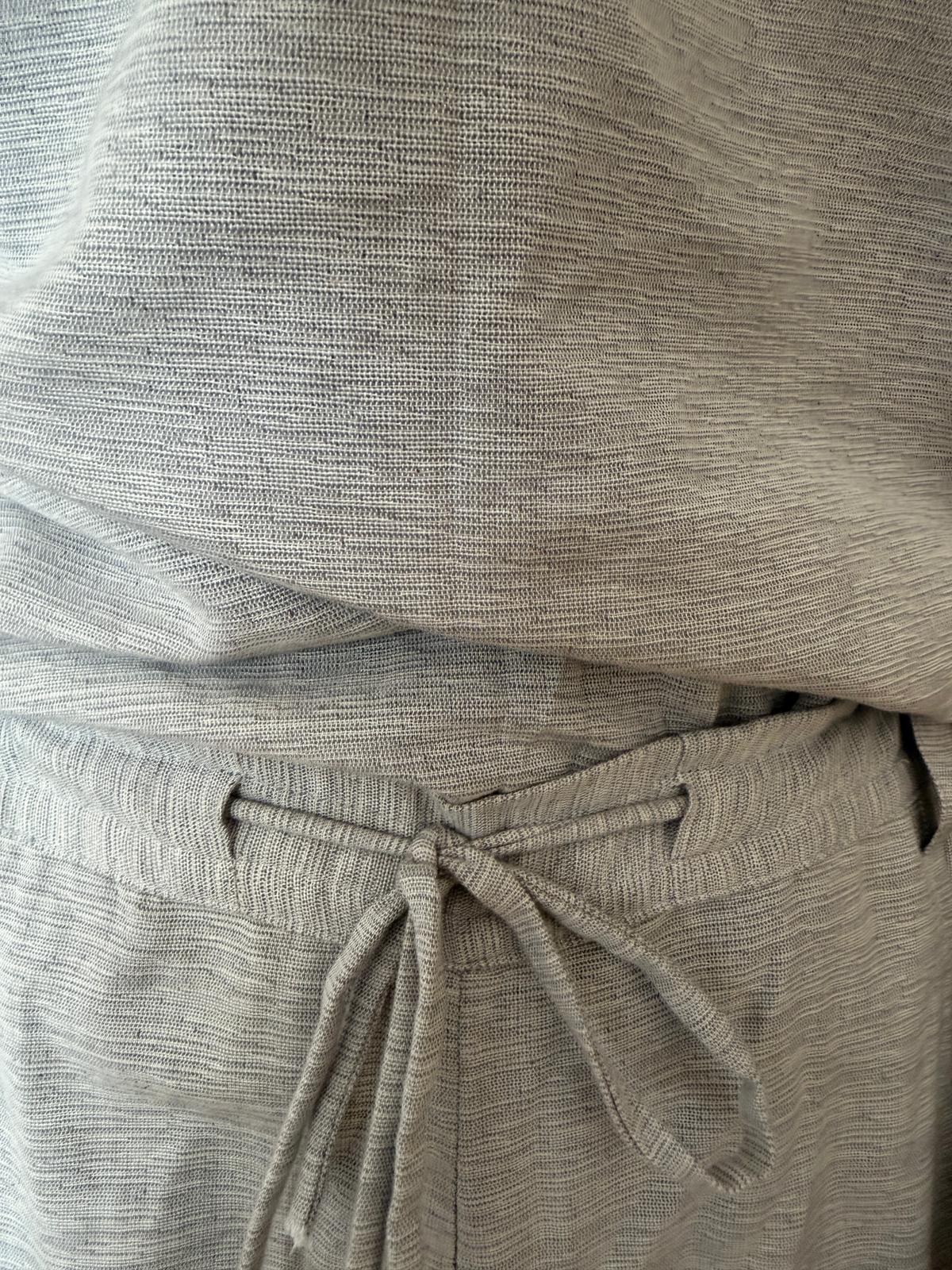 Close view of the pale grey woven fabric and fabric drawstring at the waist