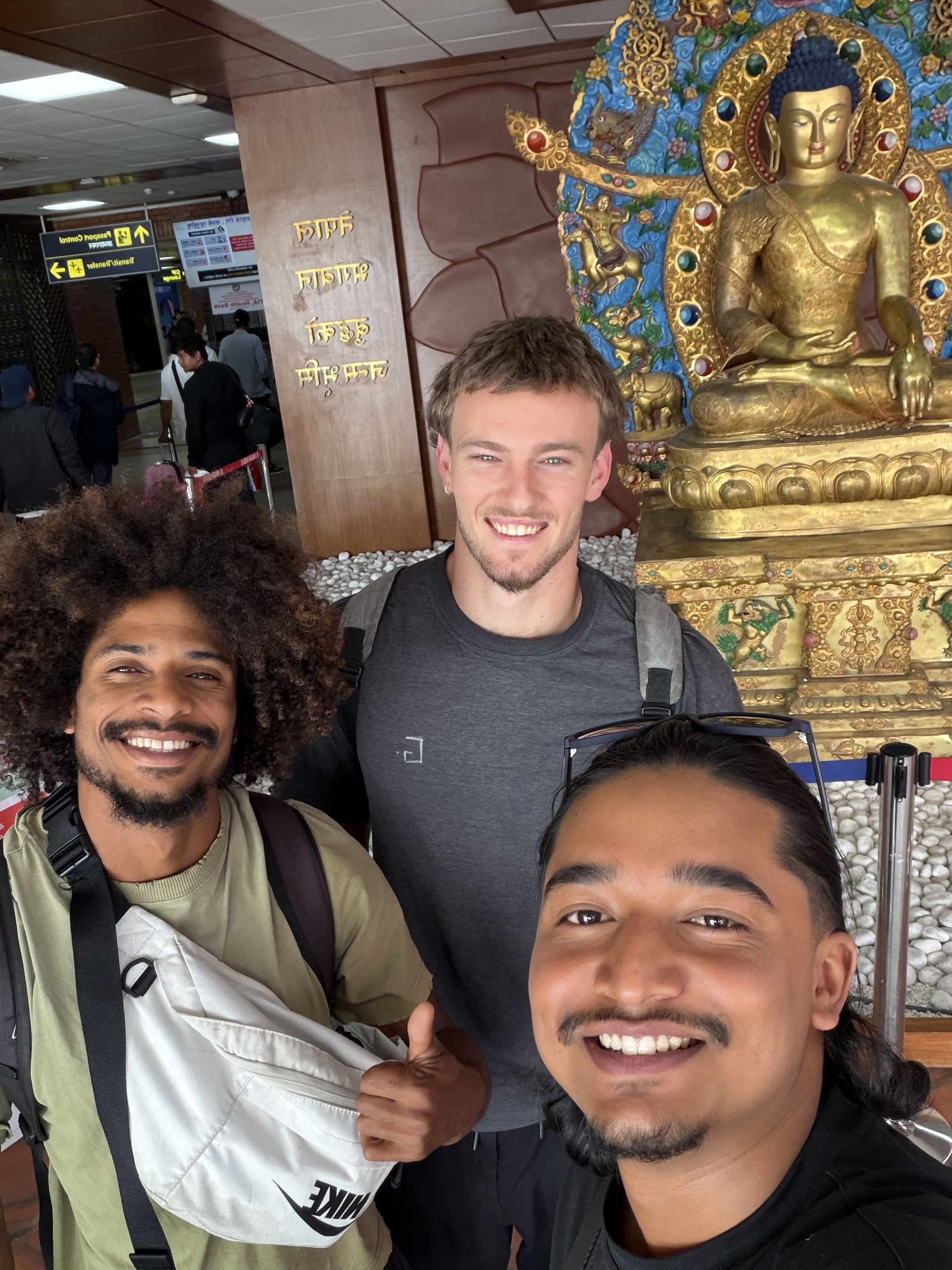 The three Jaivik founders taking a photo together in front of a golden Buddha statue at Kathmandu airport